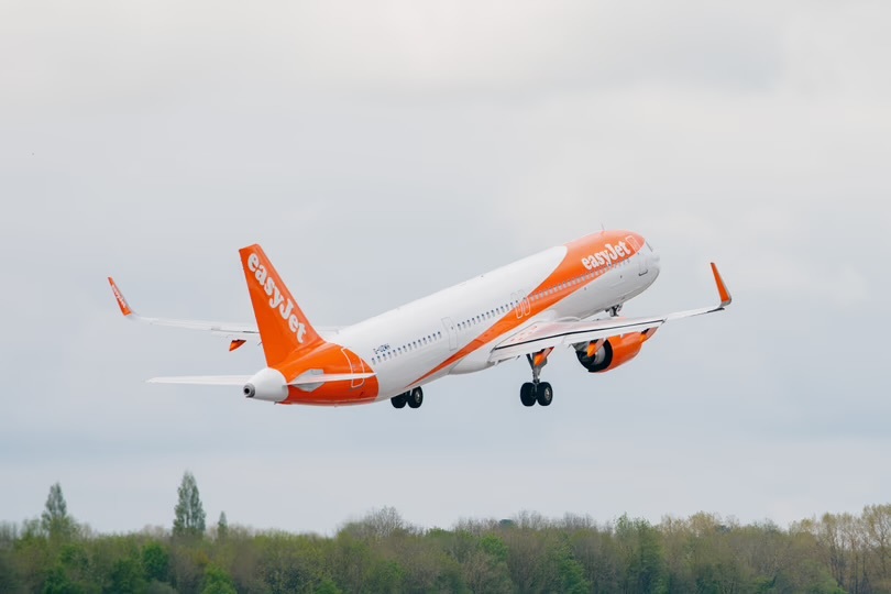 A photo of a plane painted in the EasyJet livery, taking off, flying away from the viewer